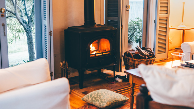 A cozy snug room has a fire lit in a wood burning stove, and comfortable seating is arranged around it.