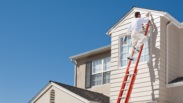 man painting house siding