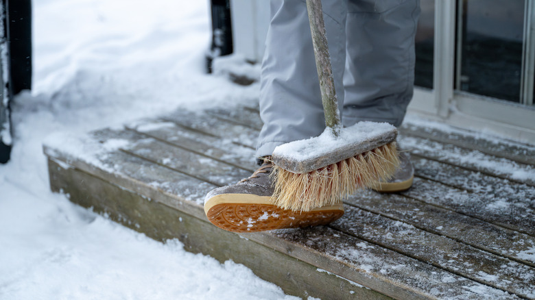 brushing off snow from deck with broom