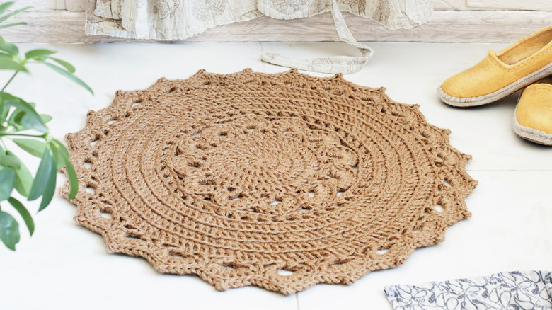 round jute rug on bathroom floor with ochre slip-ons next to it