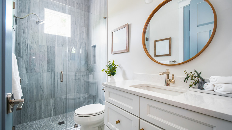 A modern bathroom with a stone shower and clear glass door.
