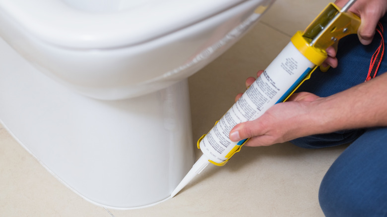 person caulking toilet