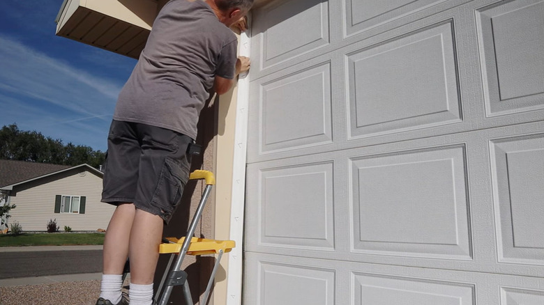 A man installing weatherstripping on garage door