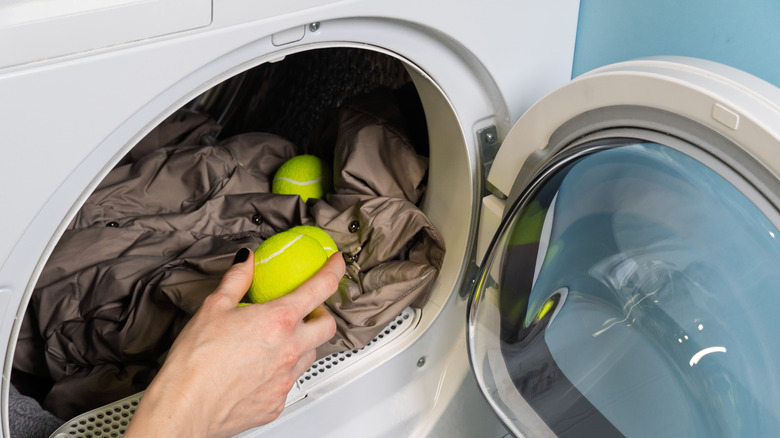 person adding tennis ball to dryer