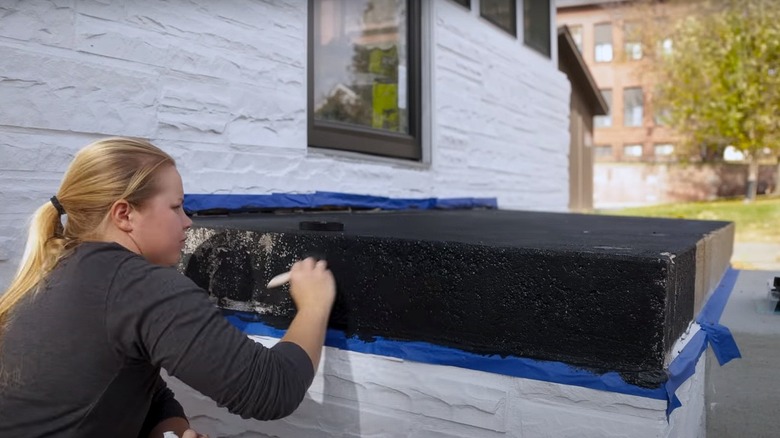 Person painting porch black