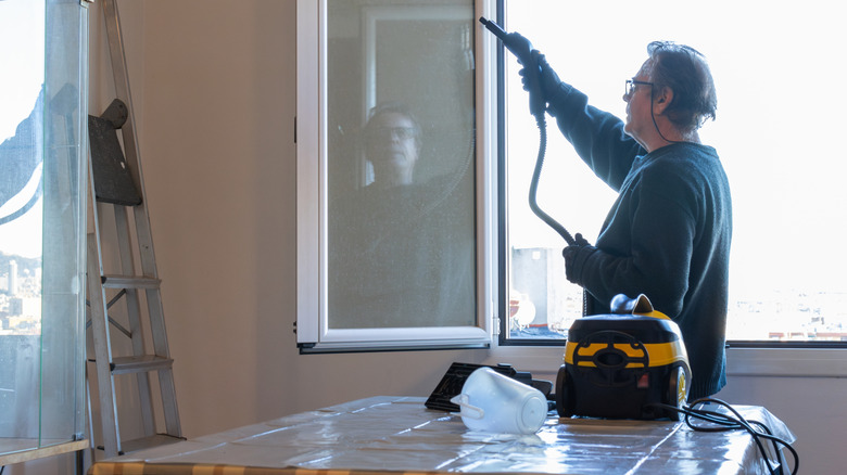 Man spraying steam on a window