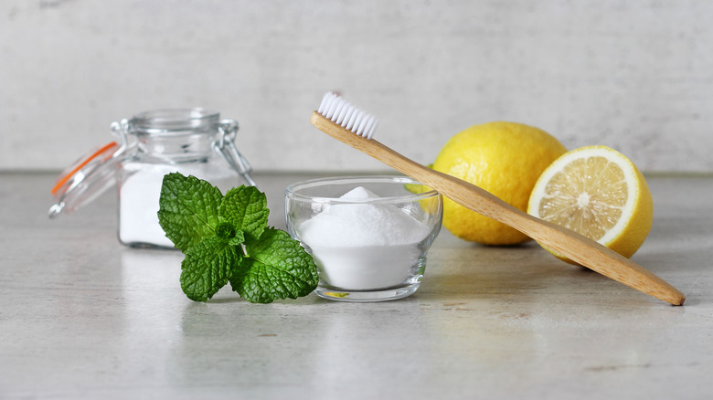 Baking soda, mint leaves, and lemon on a counter top