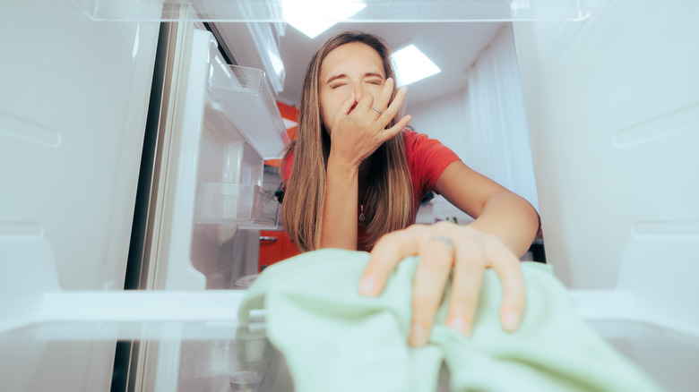 woman overwhelmed with dirty fridge
