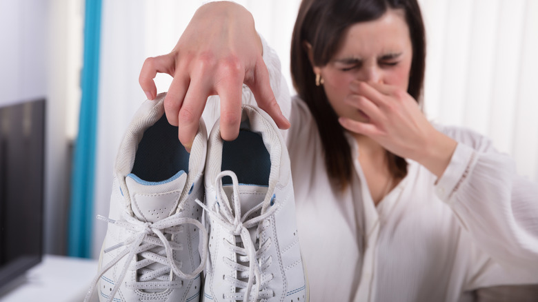 Woman holding smelly sneakers