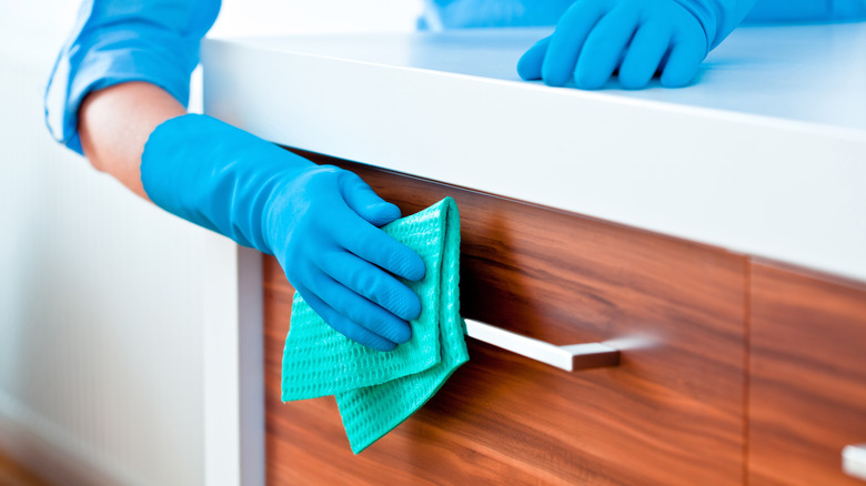 Person cleaning cabinet handle