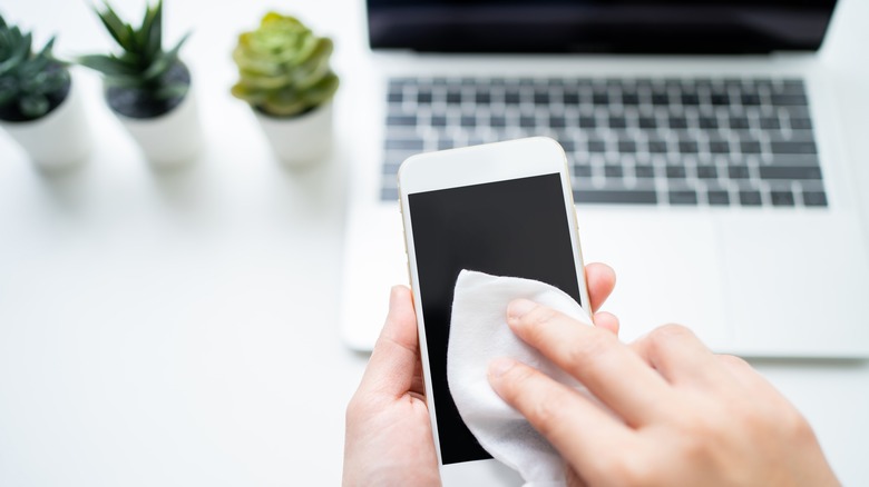 man cleaning phone and laptop