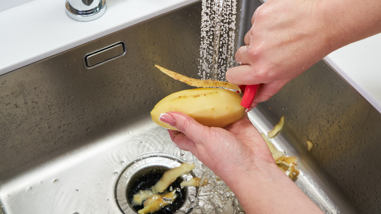 peeling potato into garbage disposal