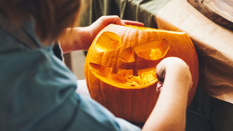 person carving face into pumpkin