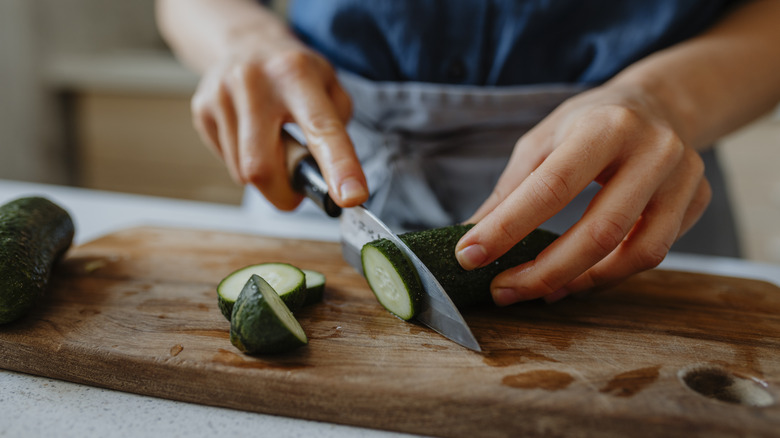 Person chopping cucumber slices