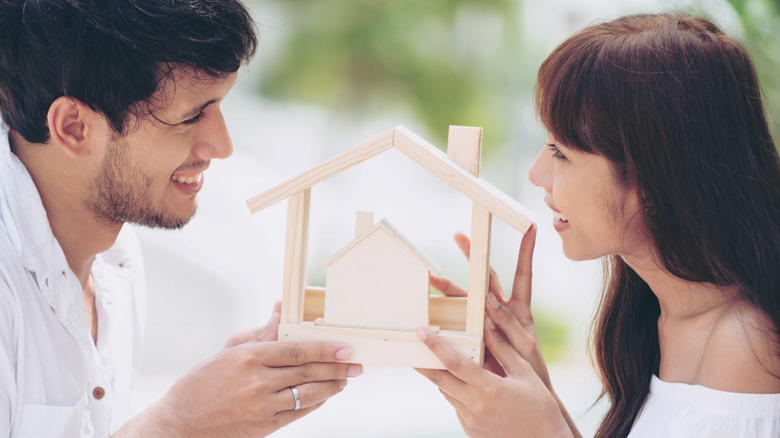 Couple holding wooden house