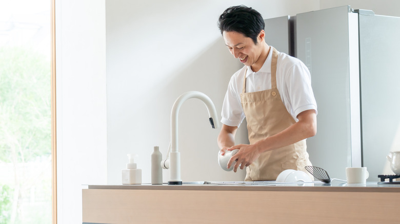 Man washing dishes at island