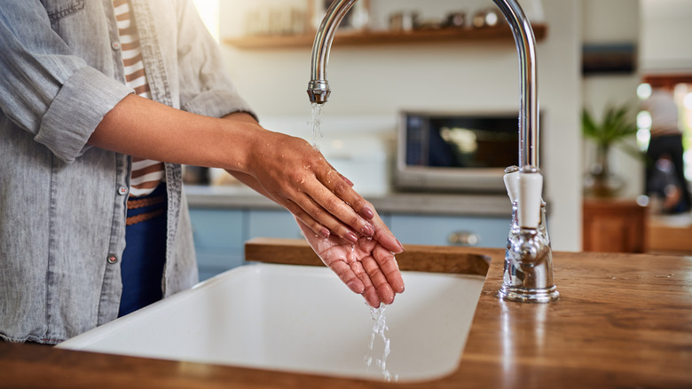 Washing hands over kitchen sink