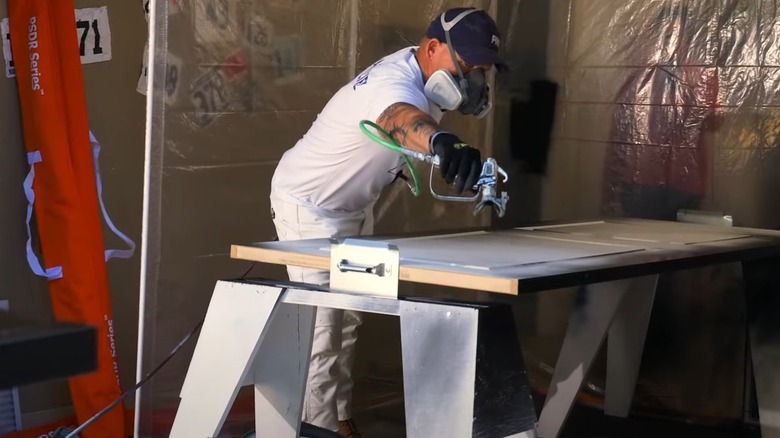 person painting a door on sawhorses