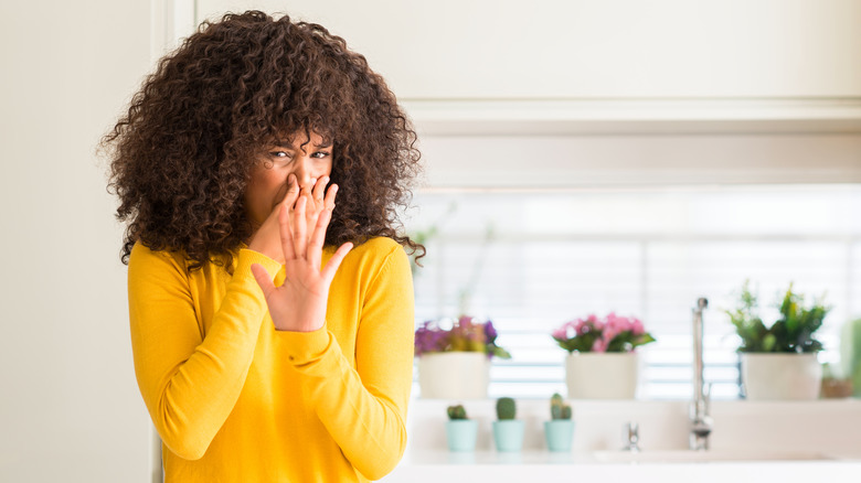 woman holding nose in kitchen 