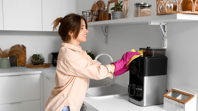 Young woman cleaning a coffee maker in a modern kitchen