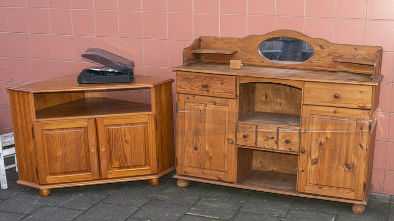 Orange oak freestanding cabinets against pink tile wall.