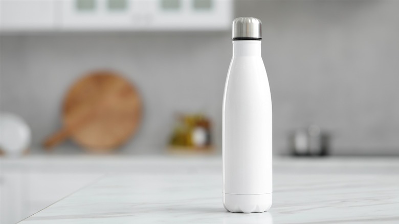white reusable stainless steel water bottle on marble kitchen counter