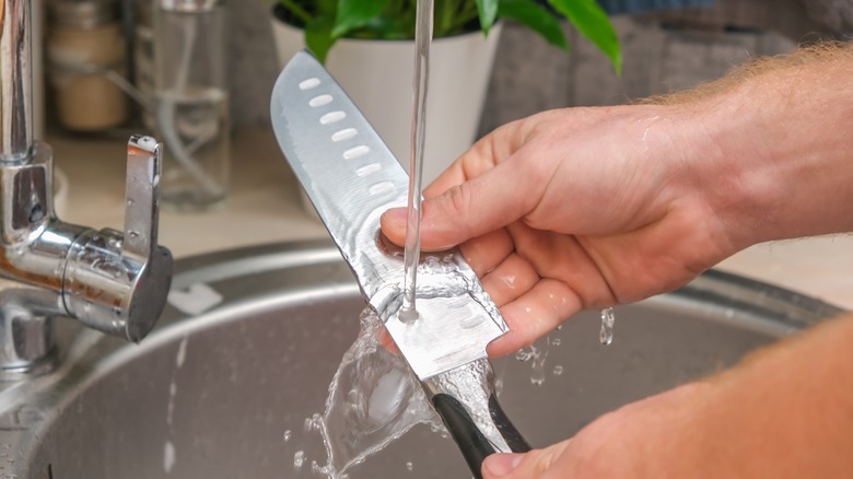 Person rinsing kitchen knife