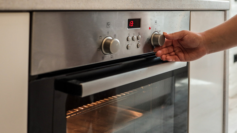 Hand adjusting temperature on oven