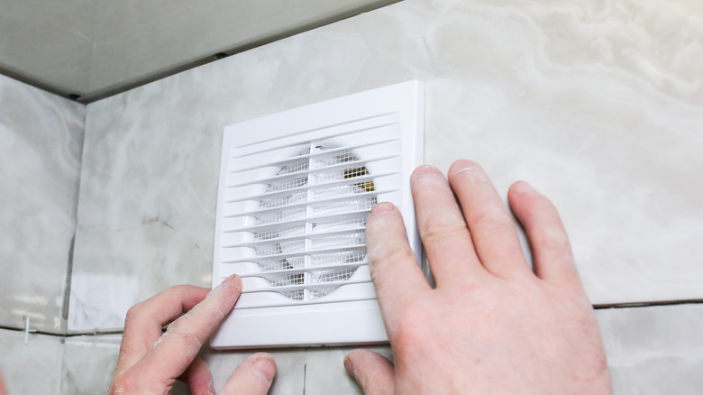 hands touching bathroom vent fan