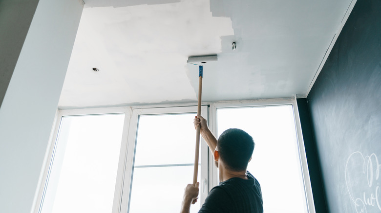 man painting ceiling gray