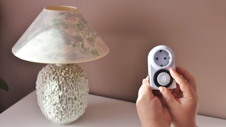 hand holding mechanical timer with lamp in background