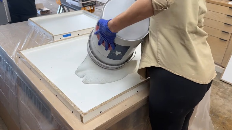 Woman pouring mixed concrete inside wood forms