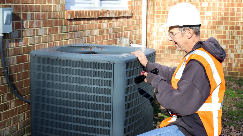 HVAC pro looking at outdoor AC condenser