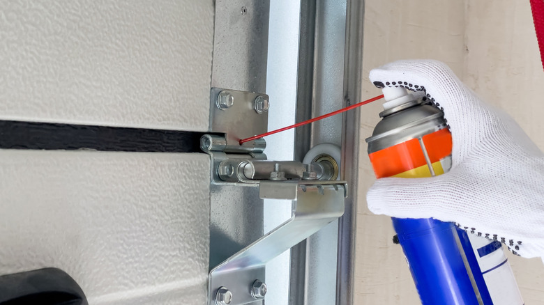 Someone lubricating a garage door