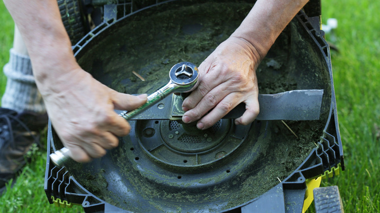 A man changing a lawn mower blade