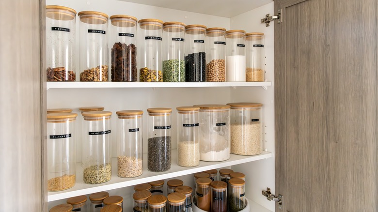 A pantry is organized with clear-sided lidded containers.