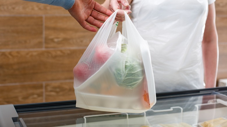 handing plastic grocery bag over