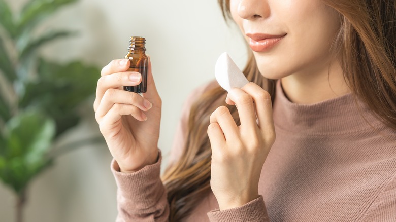 Woman holding essential oil and cotton pad