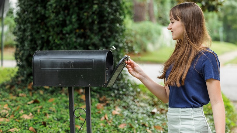 young woman opening black mailbox