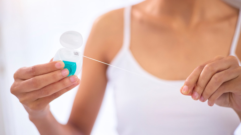 Woman holds length of dental floss