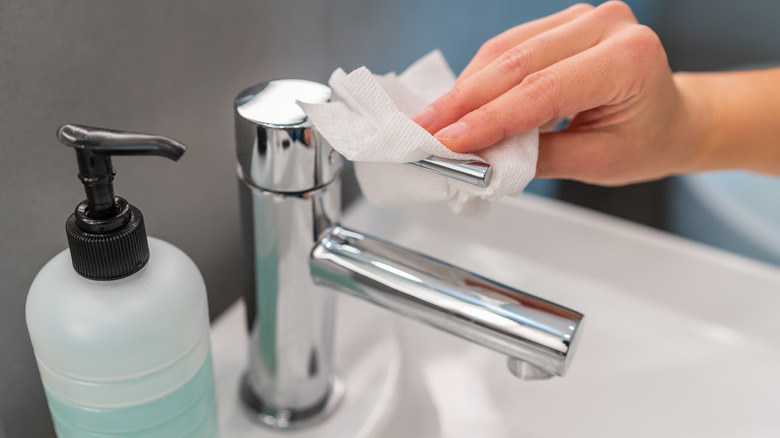 wiping faucet with disinfectant wipe
