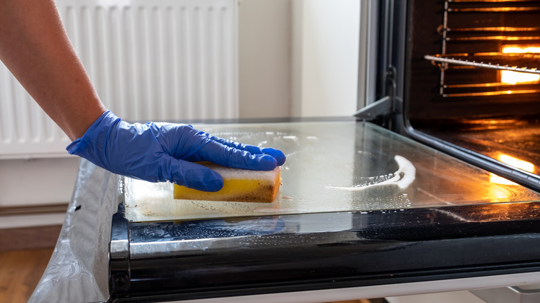 gloved hand cleaning oven door