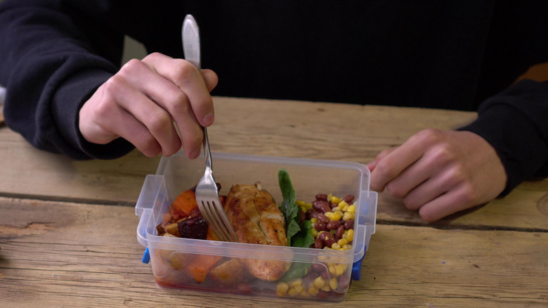 person eating from plastic food container