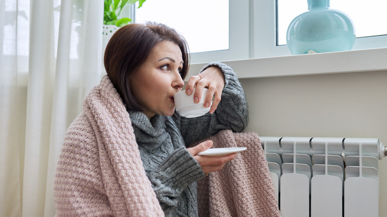 Woman warming up near heater
