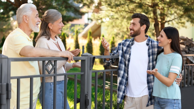 Two couples talking over fence