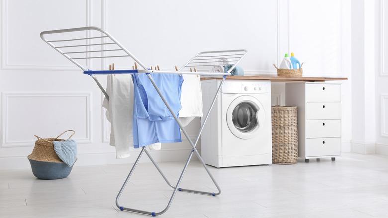 Clothes on indoor drying rack in front of washing machine