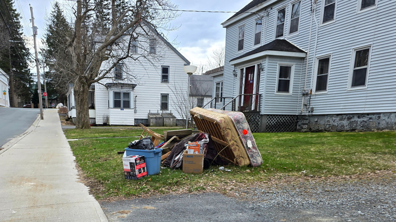 Household waste dumped outside on a lawn surrounded by houses.