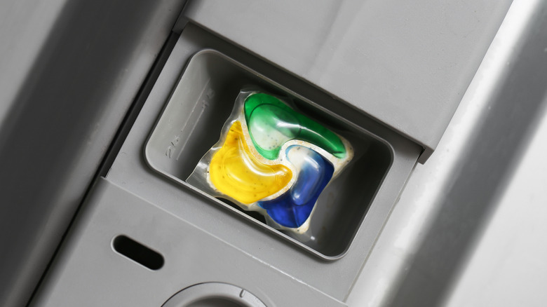 Dishwasher detergent dispenser with yellow, green, and blue detergent pod