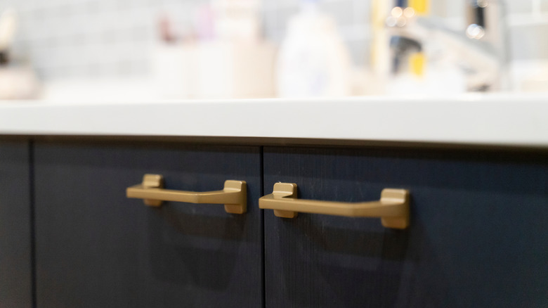 Matte gold modern kitchen cabinet hardware on a black cabinet in a kitchen