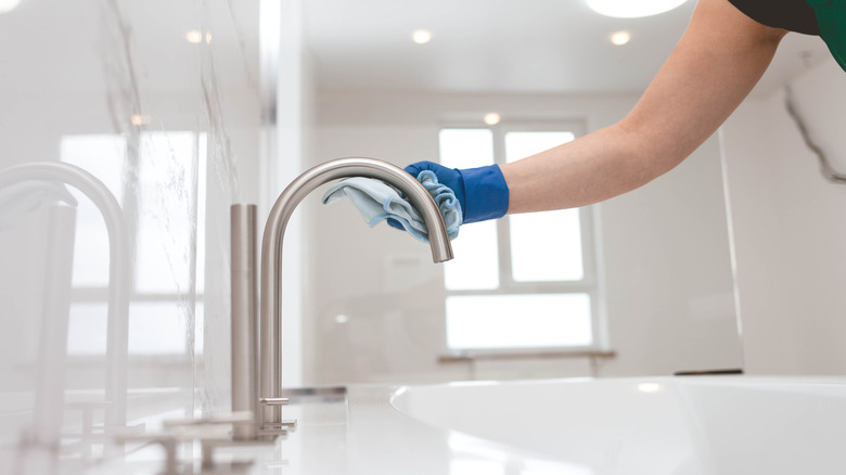 Person polishing a bathtub fixture